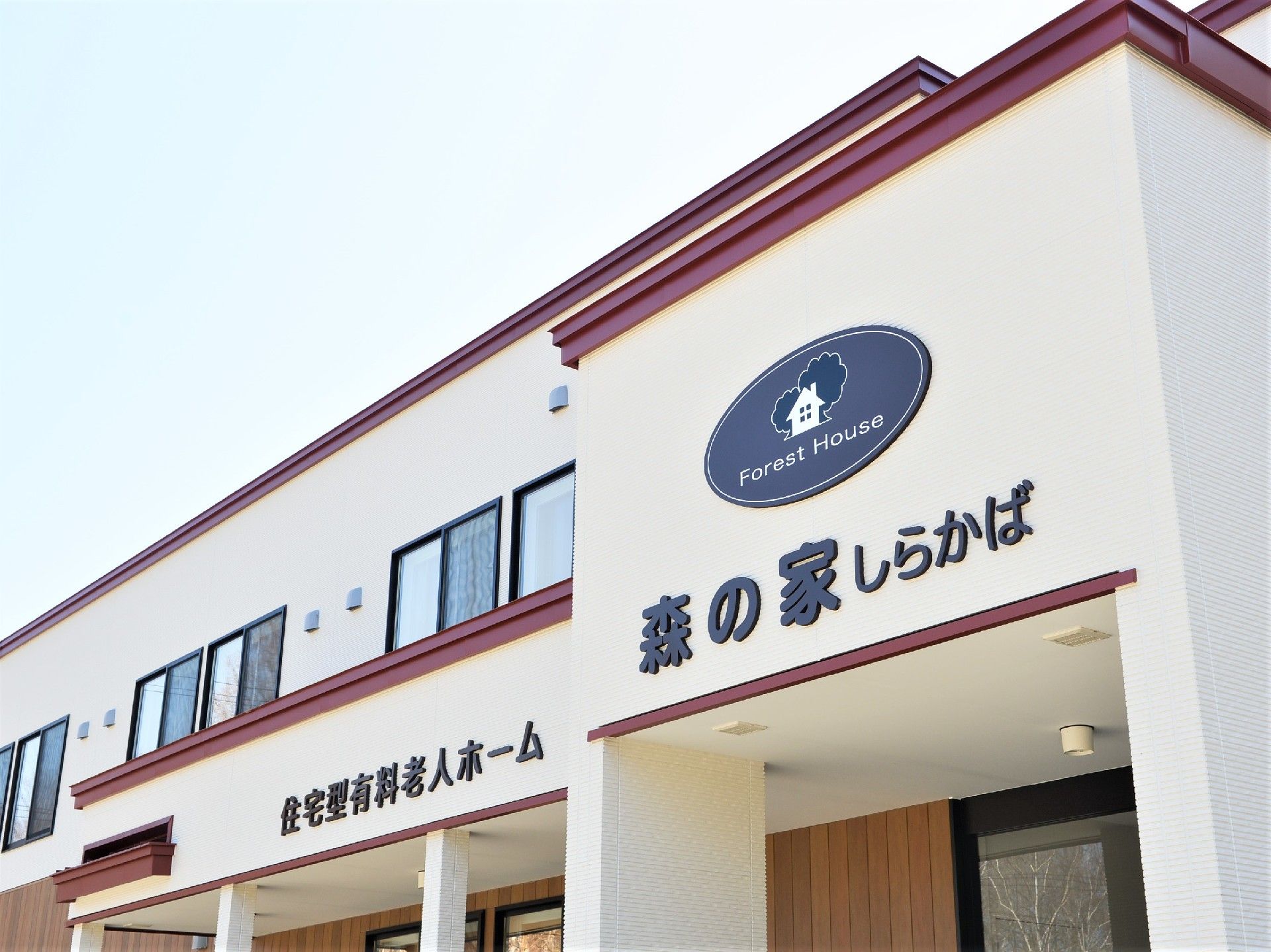 赤いラインが印象的な施設の外観。テラスやスロープがある玄関付近