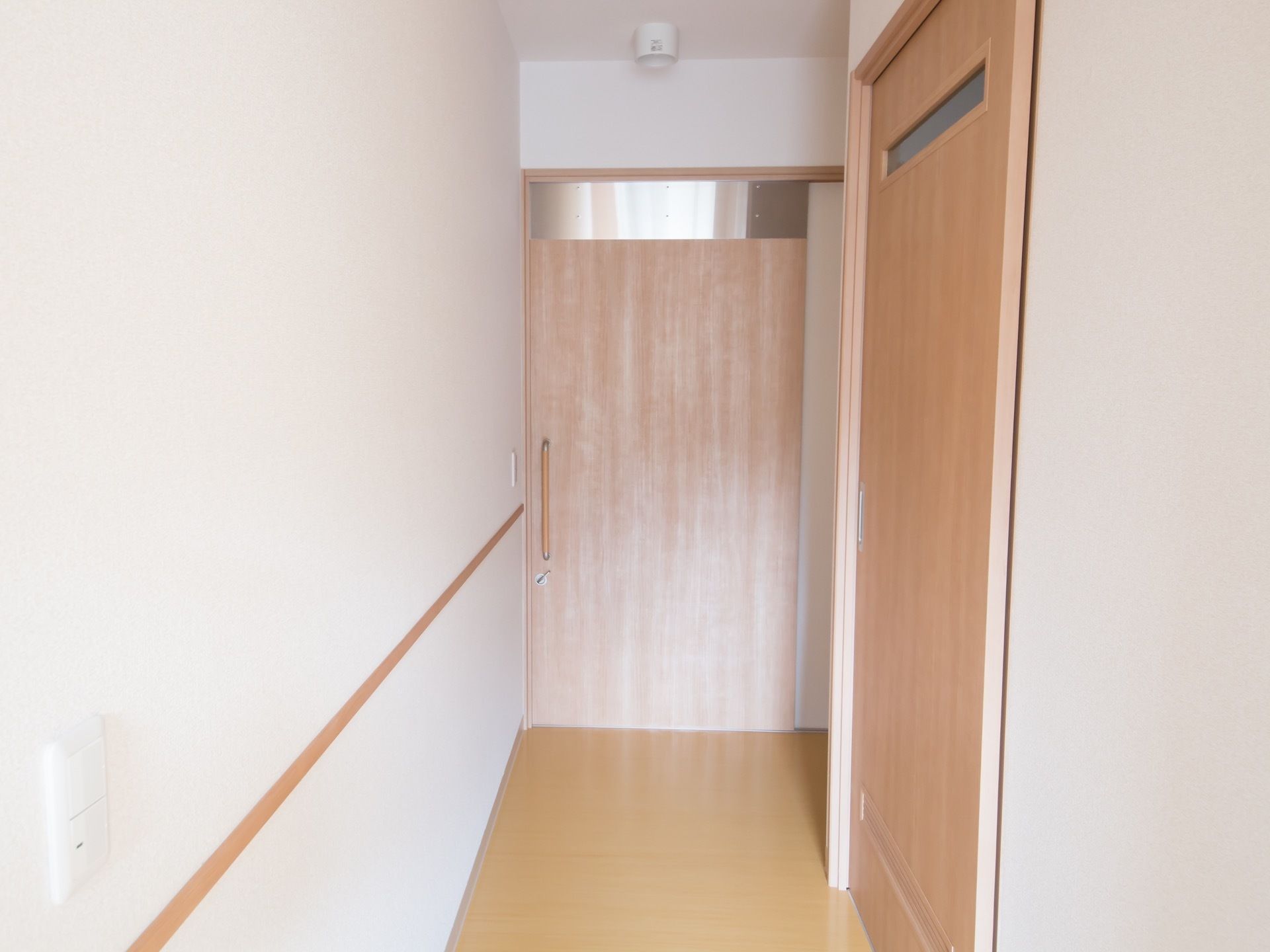 白い壁の清潔感のある居室である。居室は取っ手のあるスライド式の扉になっており、安全に開閉することができる。