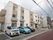 施設は、白色とベージュ色の２色の外壁になっている建物である。３階建てで、道路沿いに駐車スペースがある。