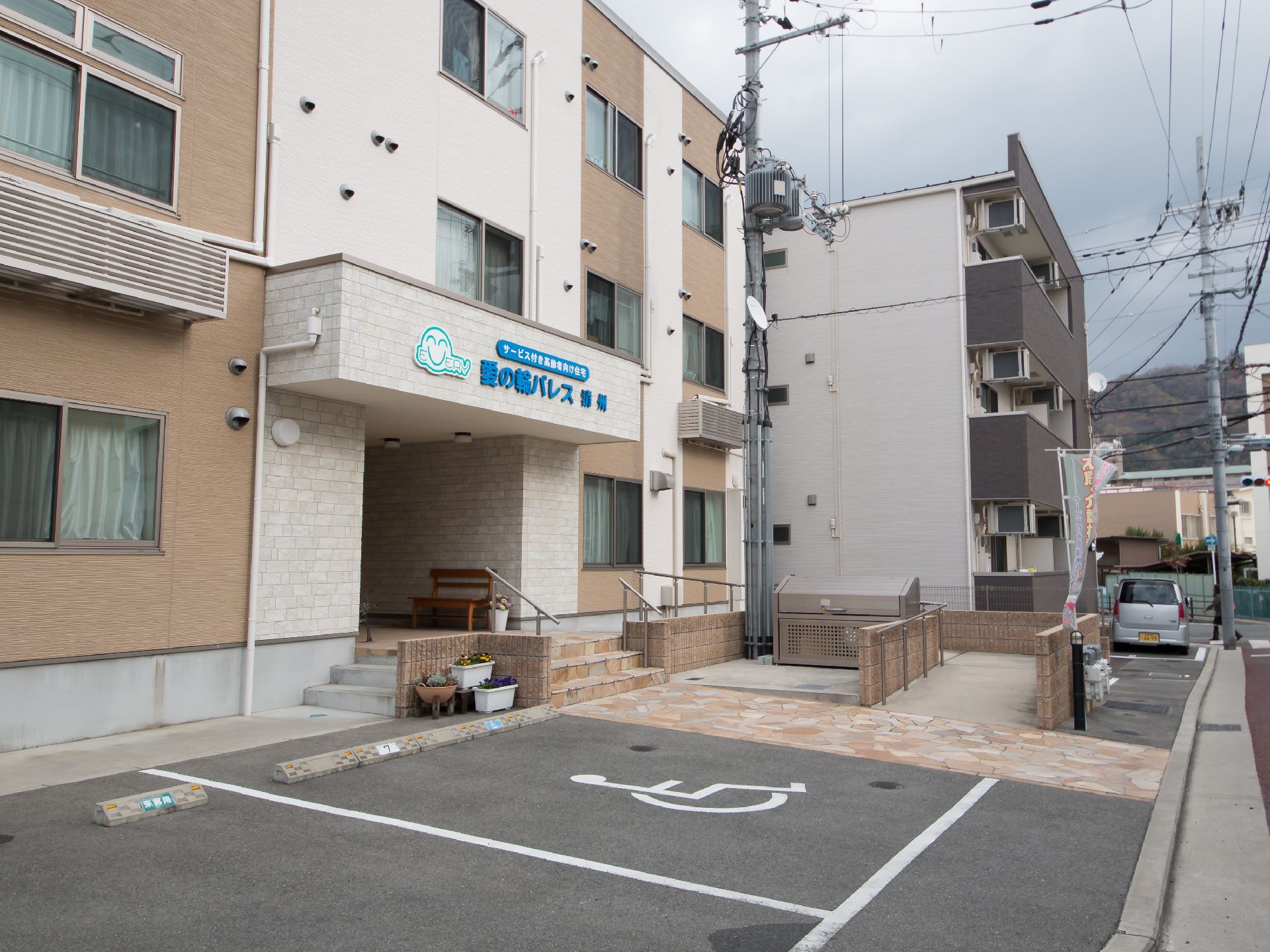 手すり付のスロープと階段がエントランスに設けられており、建物前に駐車スペースが用意されている施設