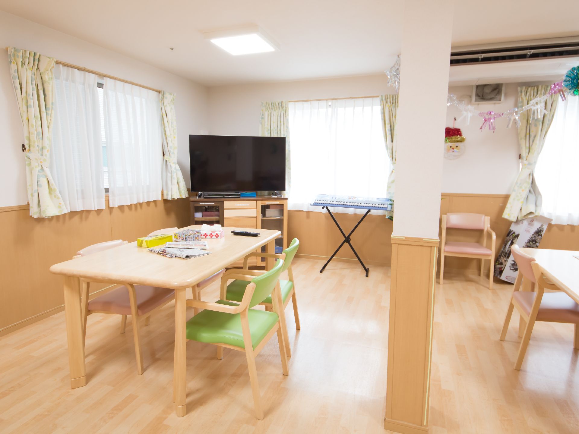明るく温かい雰囲気の空間に４人掛けテーブルやテレビが配置されているリビング