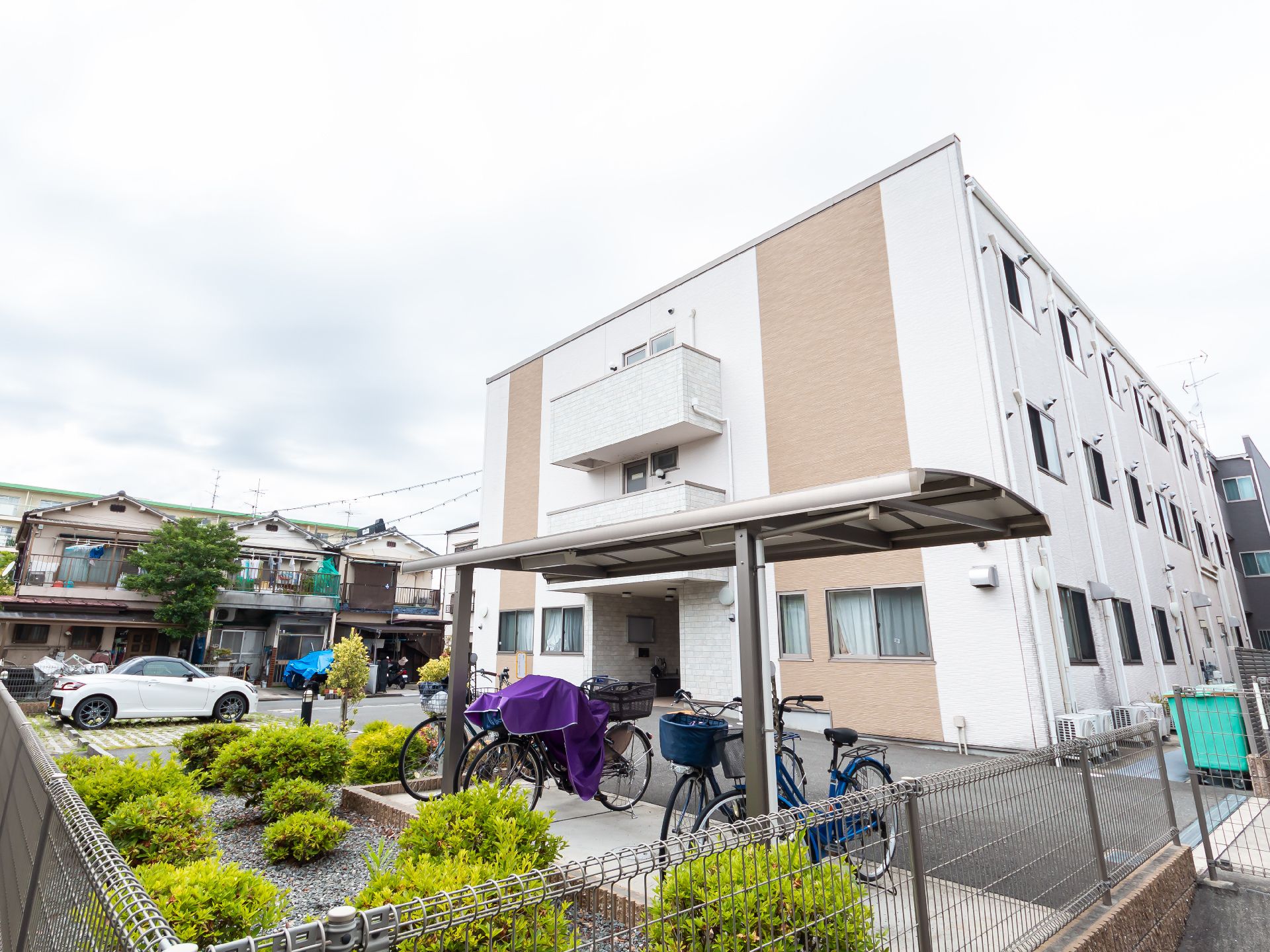 こちらを向いて笑顔になる車いすの高齢女性と介護施設の女性スタッフの様子