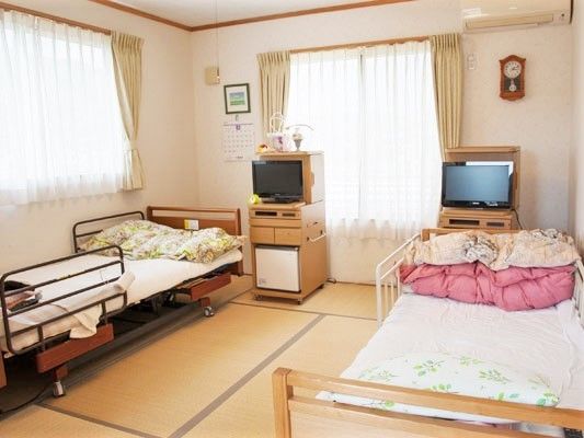 畳敷きの二人部屋。寝具付きのベッドやテレビが二つ置かれ、エアコンもついている。