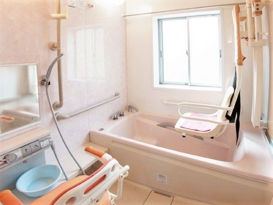 手すりがたくさんついた浴室には一人用の浴槽があり、シャワーチェアやシャワー、リフトも付いている。