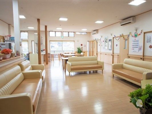 広いリビングダイニングには大きなソファがたくさん置かれ、壁には折り紙のわっか飾りやカレンダーが飾られている。