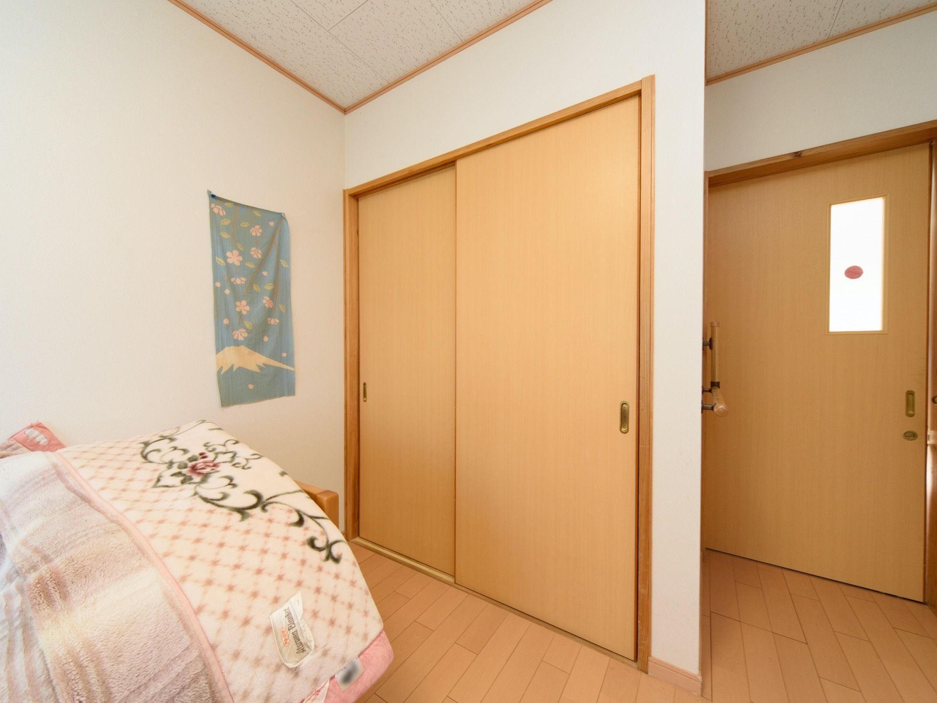居室のドア横に備え付けの収納がある。2枚の引き戸が設けられており、大きな取り出し口が確保されている。