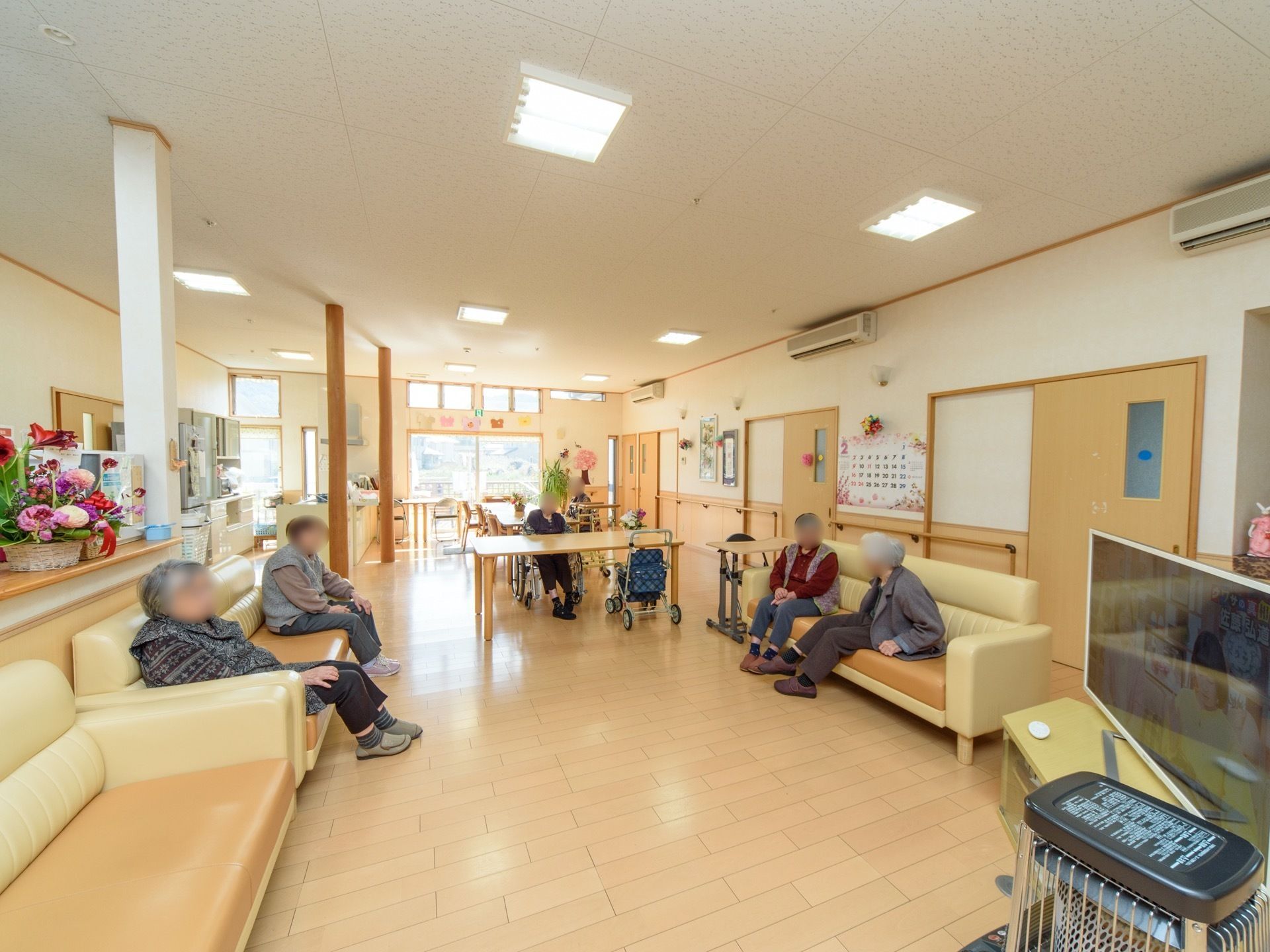 食堂の端にテレビが設置されており、それを挟むように複数のソファが置かれている。入居者様が集まって余暇を過ごしている。