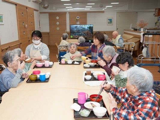 ダイニングテーブルが並んだ食堂は、落ち着いた雰囲気。食事を楽しむ入居者と介助に当たるスタッフ。