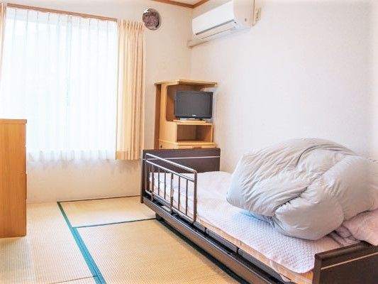 エアコンやカーテン付きの大きな窓が付いた居室は畳敷きの和室でベッドもある。