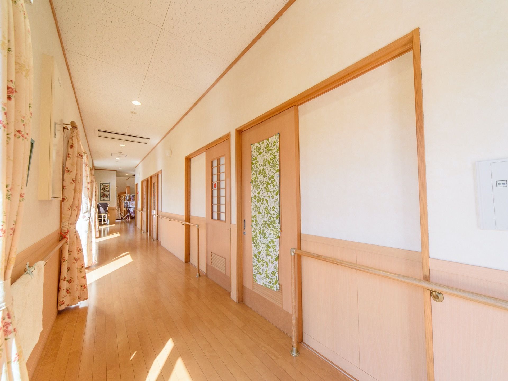 廊下には手すりが備わっており広々としているので、歩行の訓練を行うことができる。居室の扉は褐色のスライド式である。