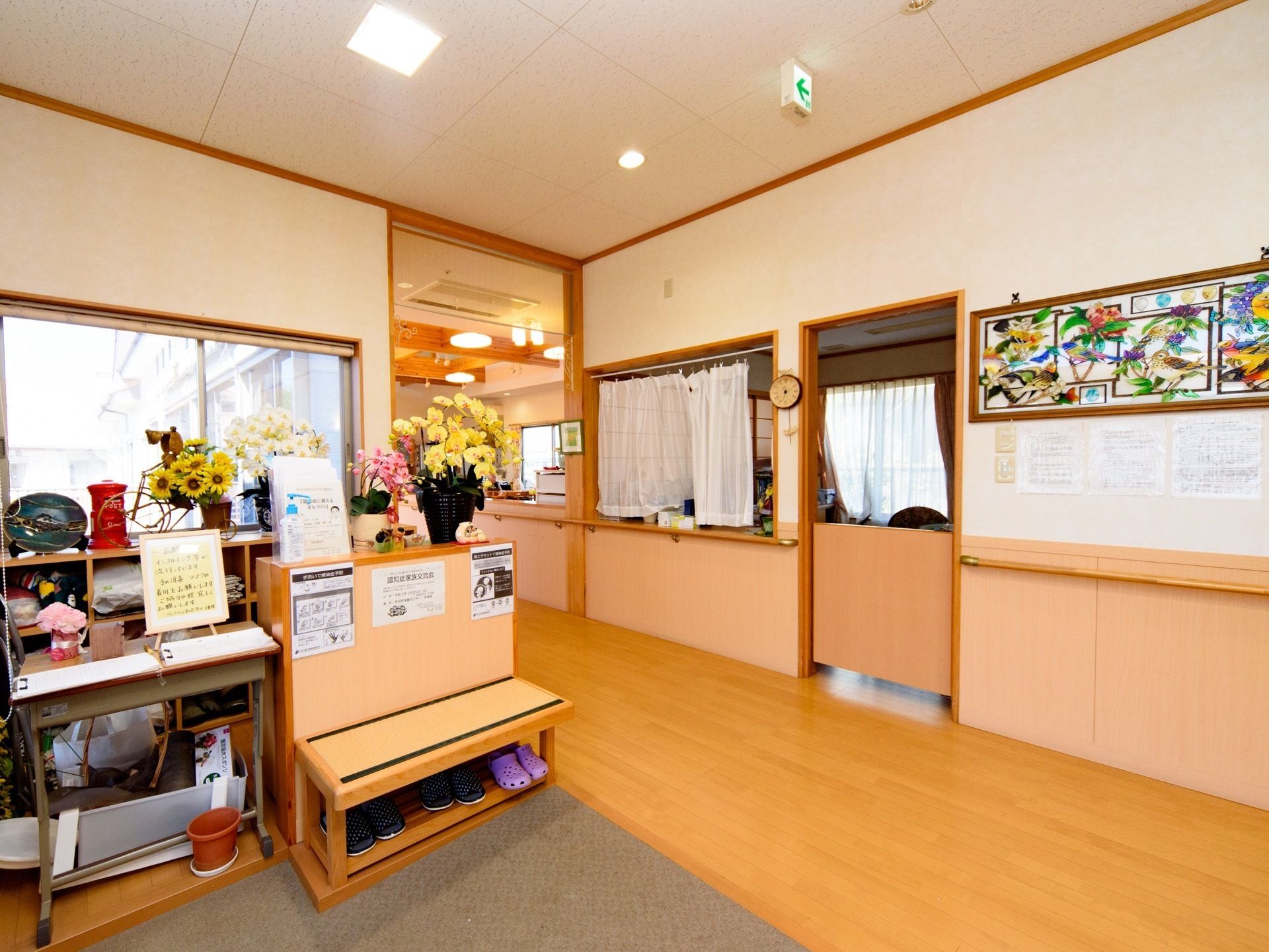 玄関ホールには色とりどりの花が飾られている。目の前は事務室である。靴を履き替える際に腰掛けることのできる椅子が用意されている。