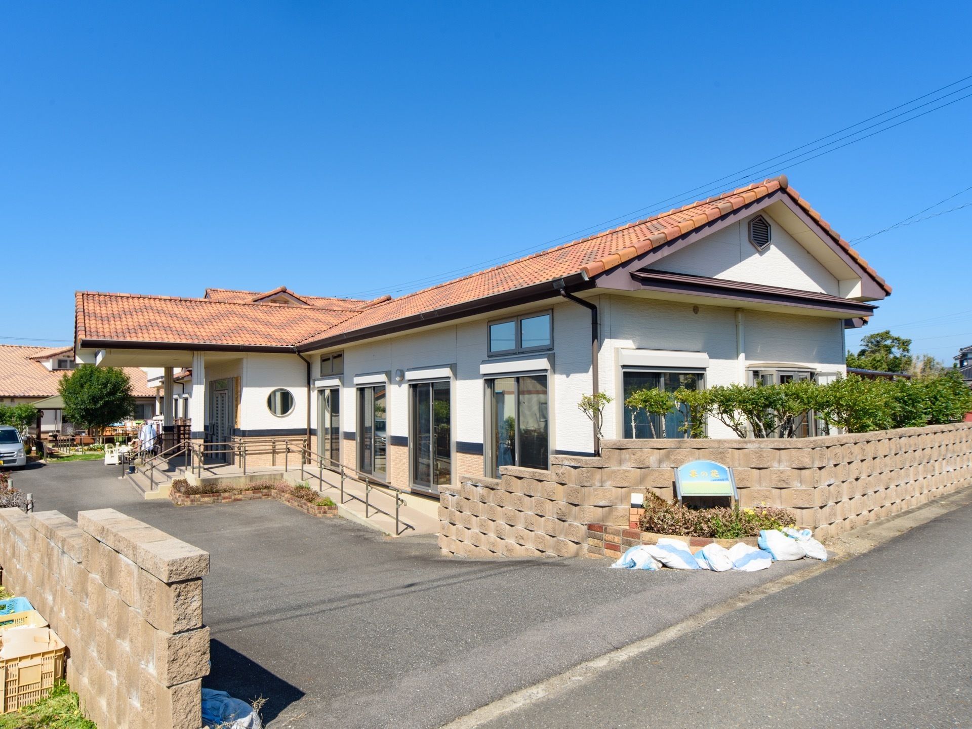 施設周辺には大きな建物がないので日当たり良好である。玄関には階段とスロープが備わっている。平屋造である。