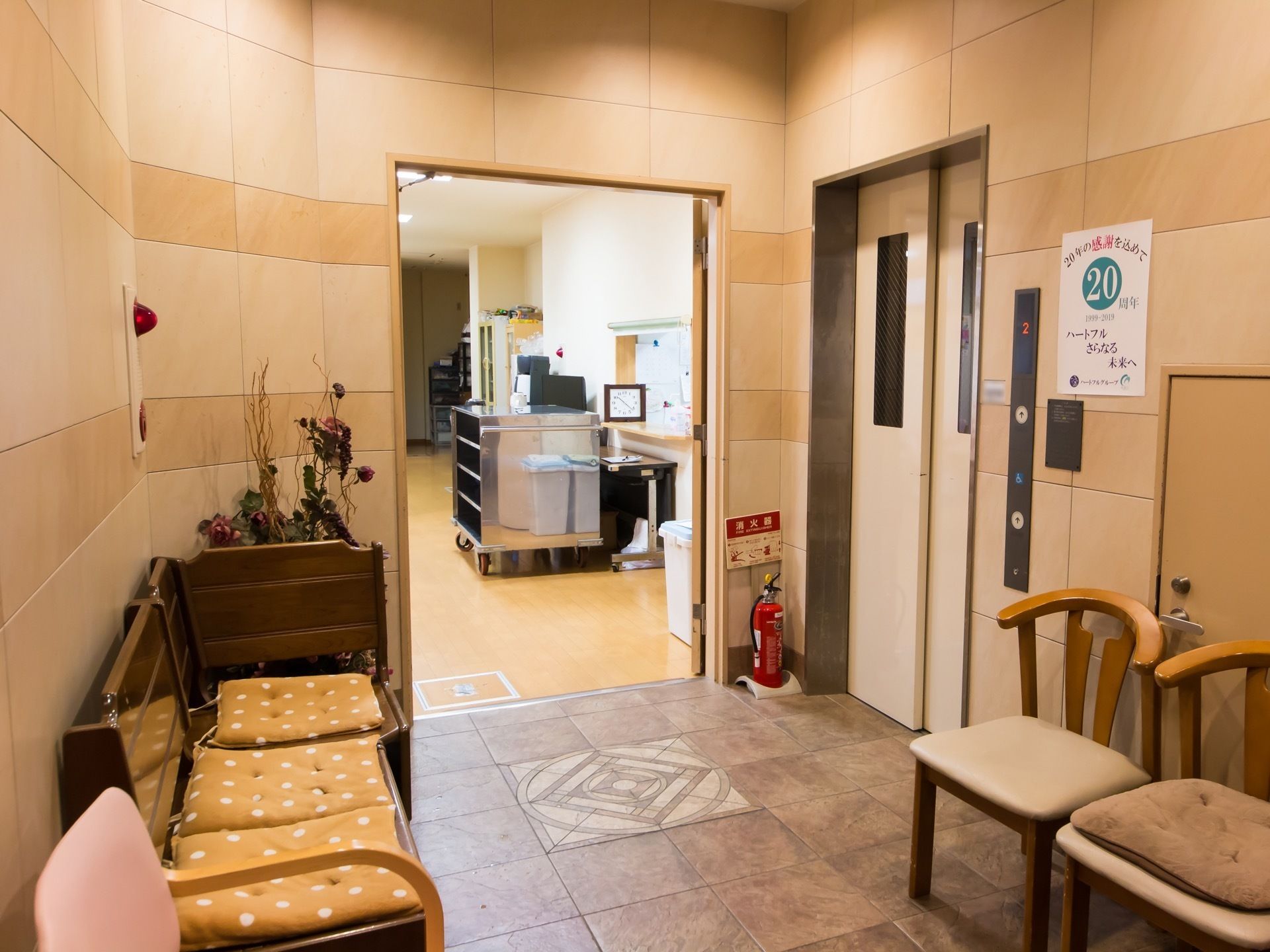 エレベーターが設置されているスペースに、ベンチや複数の椅子が置かれている。座面には座布団が用意されている。