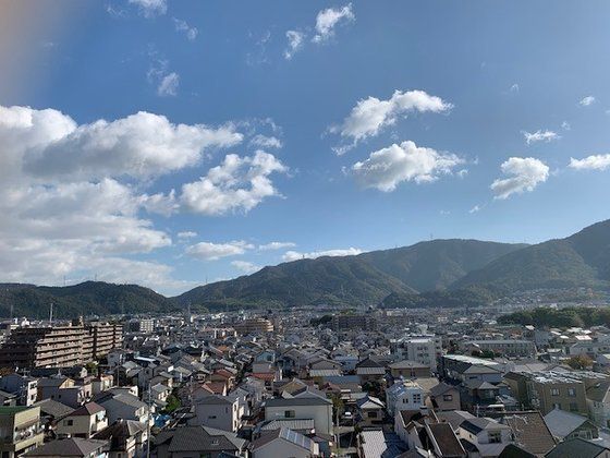 青空の下にたくさんの住宅が建っていて、奥には山々が連なっている。