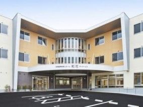 広い駐車スペースがある、茶色い外壁の3階建て建築物
