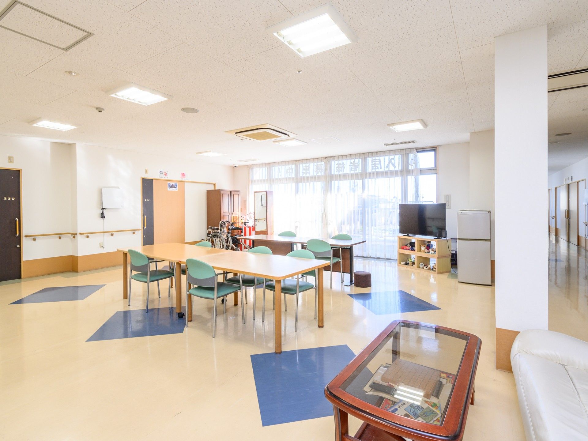 グリーンの椅子とベージュの机の組み合わせが複数ある広い空間