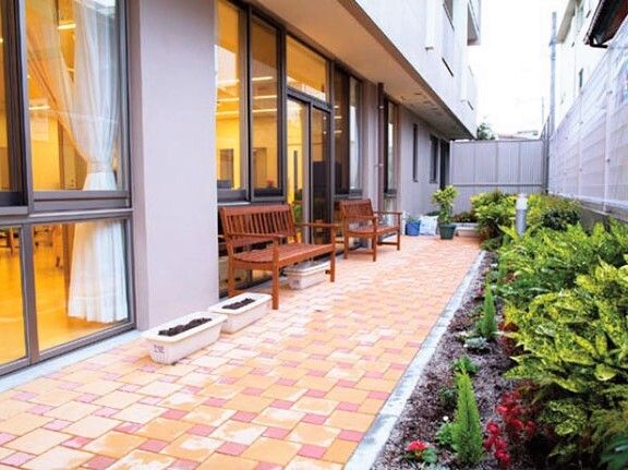 木製のベンチやプランターが置かれたテラスは共有スペースから出入りが可能。中庭には季節の花が植えられている。