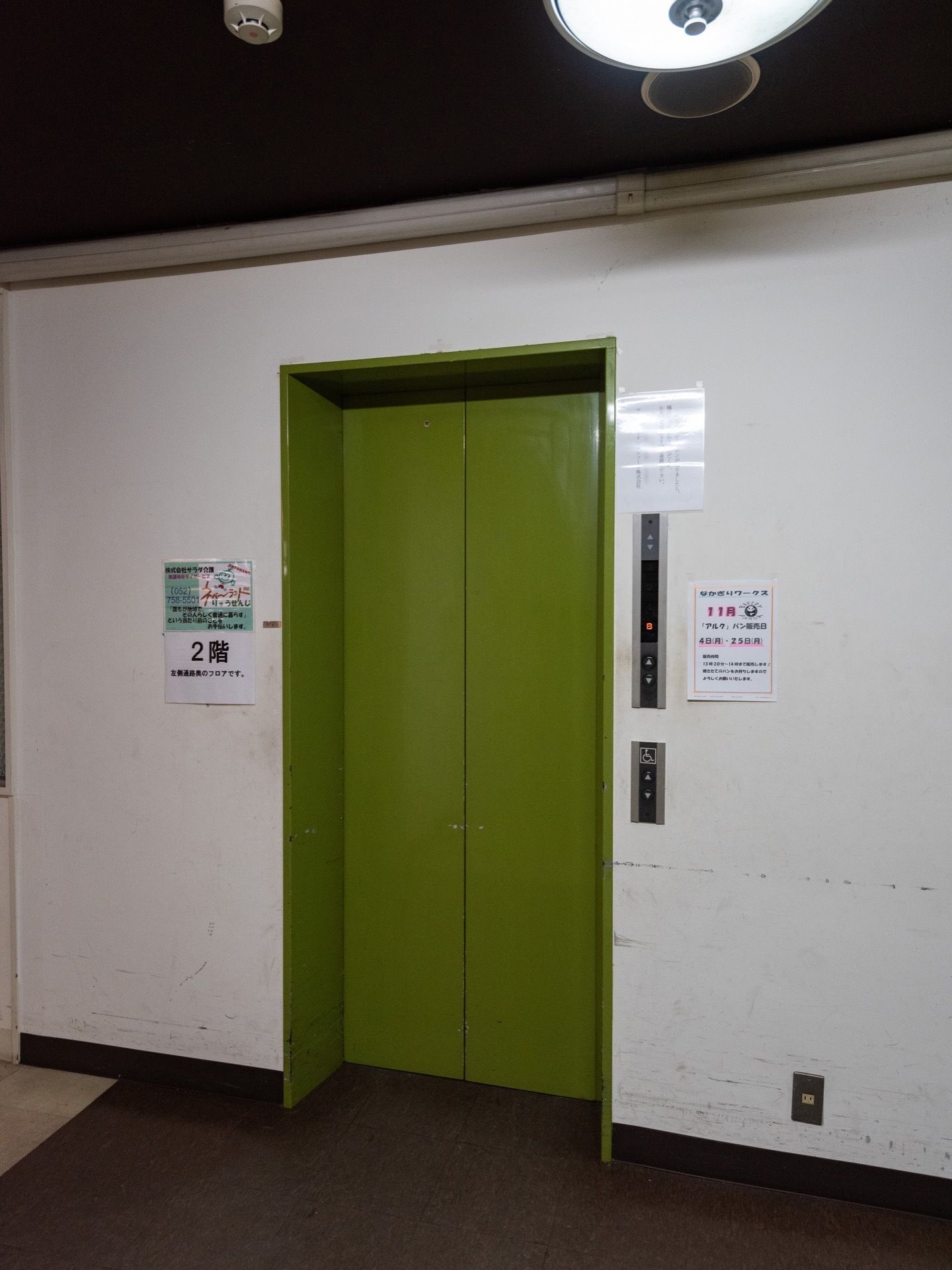 館内に設置されているエレベーターである。緑色の鉄の扉が閉まっており、向かって右側の壁に呼び出しボタンがある。