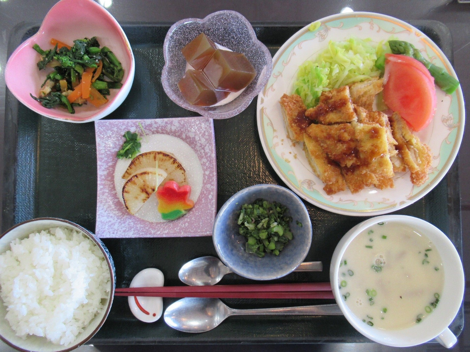 肉のソテーにサラダが添えられ、炊き込みご飯や五目煮、デザートなどが並んでいる。