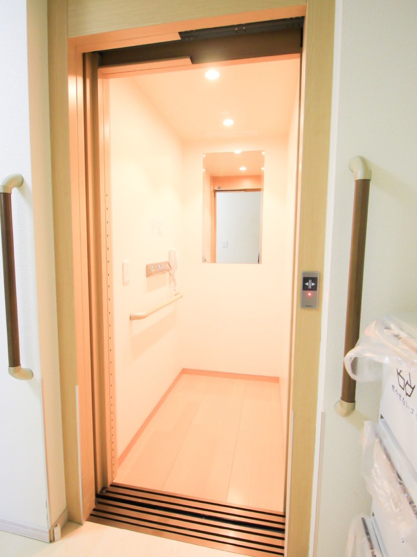 車椅子対応エレベーターである。鏡や緊急連絡用電話機、手すりが内部に完備されている。資源分別ごみ箱が壁際に置かれている。