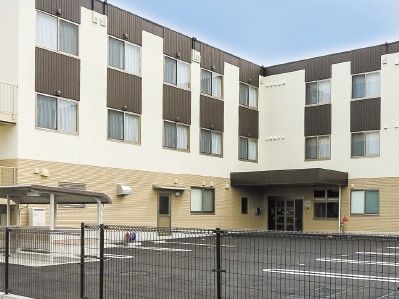 無駄のない直線的な外観の施設のデザイン。出入り口付近医駐車場と雨除けのひさし