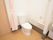 居室に完備されたトイレである。壁に呼び出しボタンとL型手すりがある。扉には、カーテンが採用されている。