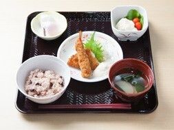 赤飯にエビフライ、みそ汁、デザート、ポテトサラダなどが並んだトレー。