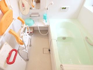 白い浴槽が置かれた広い浴室。シャワーや手すり、ボードも設置されている。
