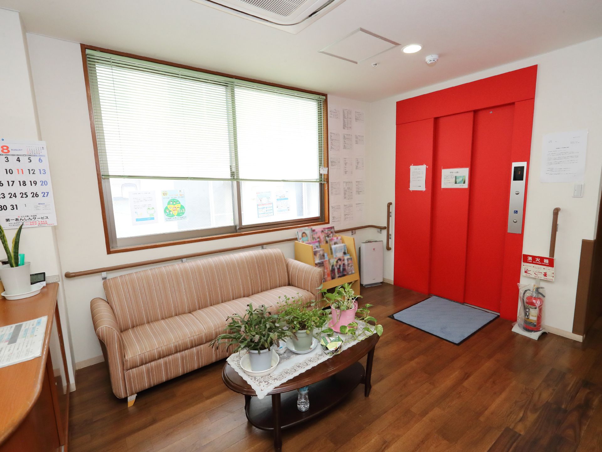 高齢者2名とスタッフが手を握りながら談笑している様子。施設内の会話の一画面
