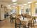 四人掛けのテーブルと椅子が複数組並んでいる施設内のリビングスペース