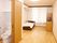 スライド式のドアが付いたトイレが設置されたフローリングの部屋には大きな窓があり、介護ベッドや収納家具もある。