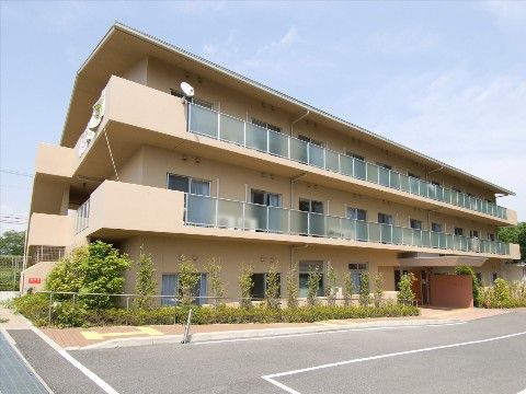 三階建ての建物で、居室前には掃き出し窓が付いている。玄関前は平坦で、玄関上には庇がある。建物に沿って植栽がある。