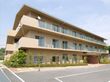 三階建ての建物で、居室前には掃き出し窓が付いている。玄関前は平坦で、玄関上には庇がある。建物に沿って植栽がある。