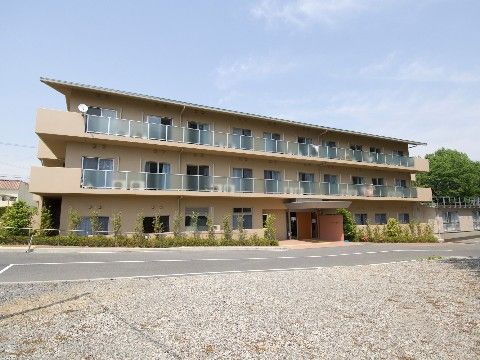 勾配の付いた道路際に立地するベランダを完備した3階建ての施設外観