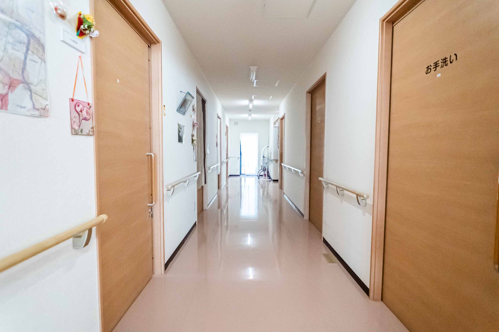 なにかを見て笑顔で手をたたいている高齢女性とスタッフの様子。施設での一場面の写真