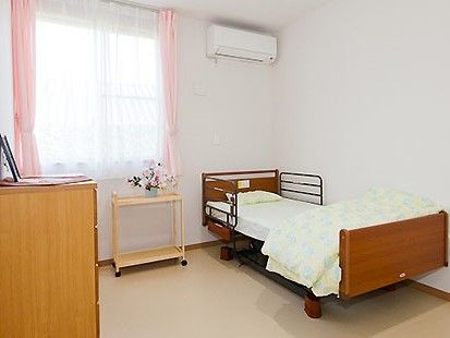 介護用ベッドが置いてある小さな部屋。エアコンやたんすなど日用品が置いてある様子