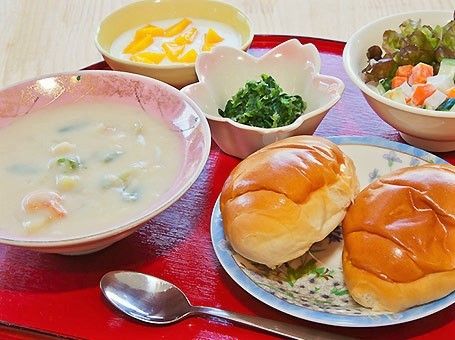 シチューとサラダ、パンが乗っているトレー。施設で出されている食事のメニュー例