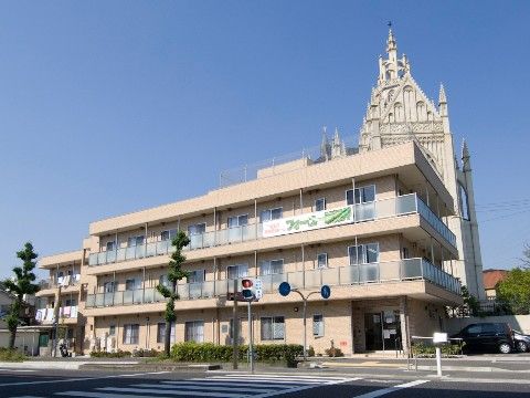 前面に横断歩道、背景に教会が立地している3階建ての施設