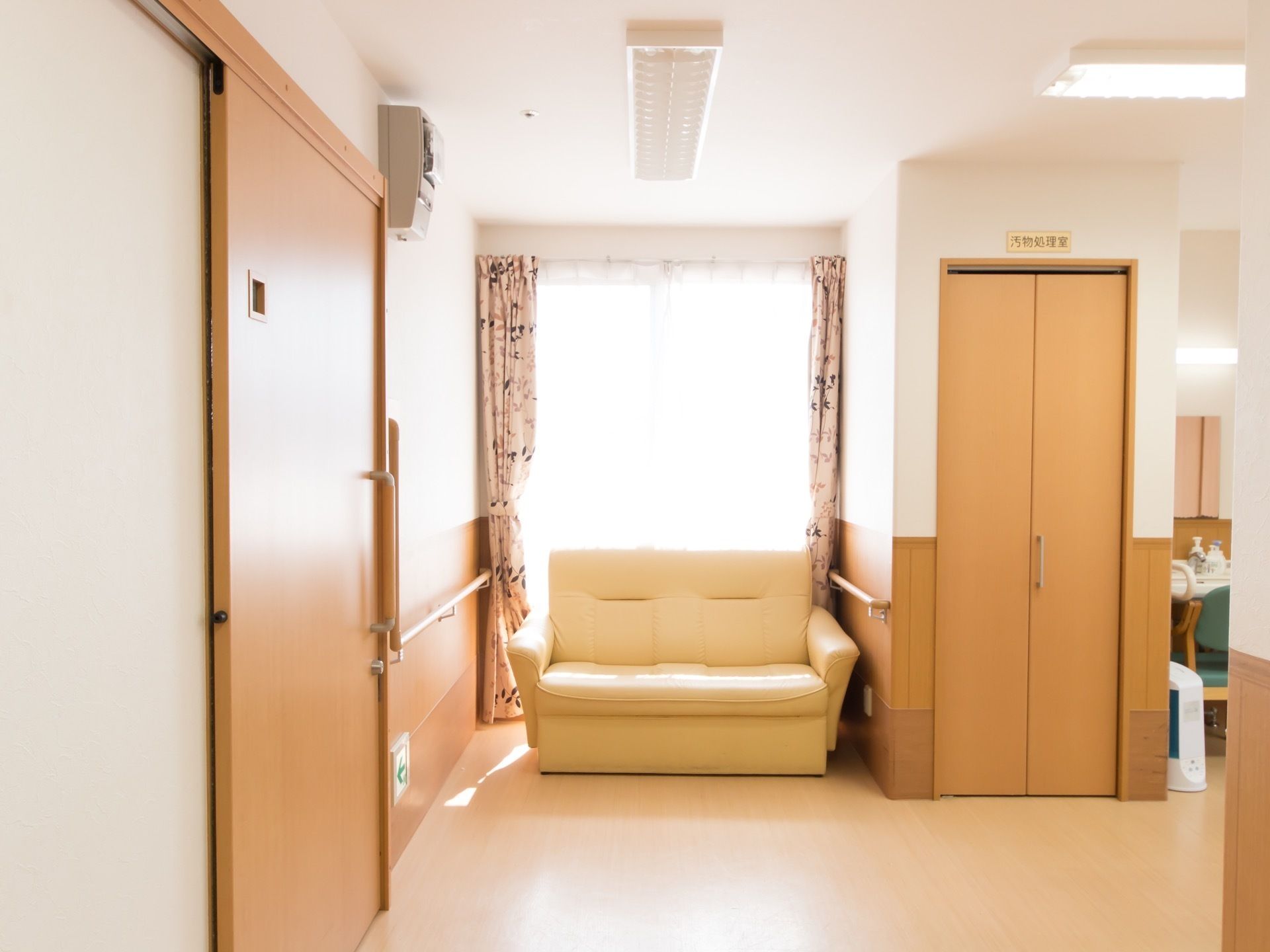 大きな窓の前にソファが置かれている。手すりが壁に取りつけられている。間口の広いスライド式の扉がある。
