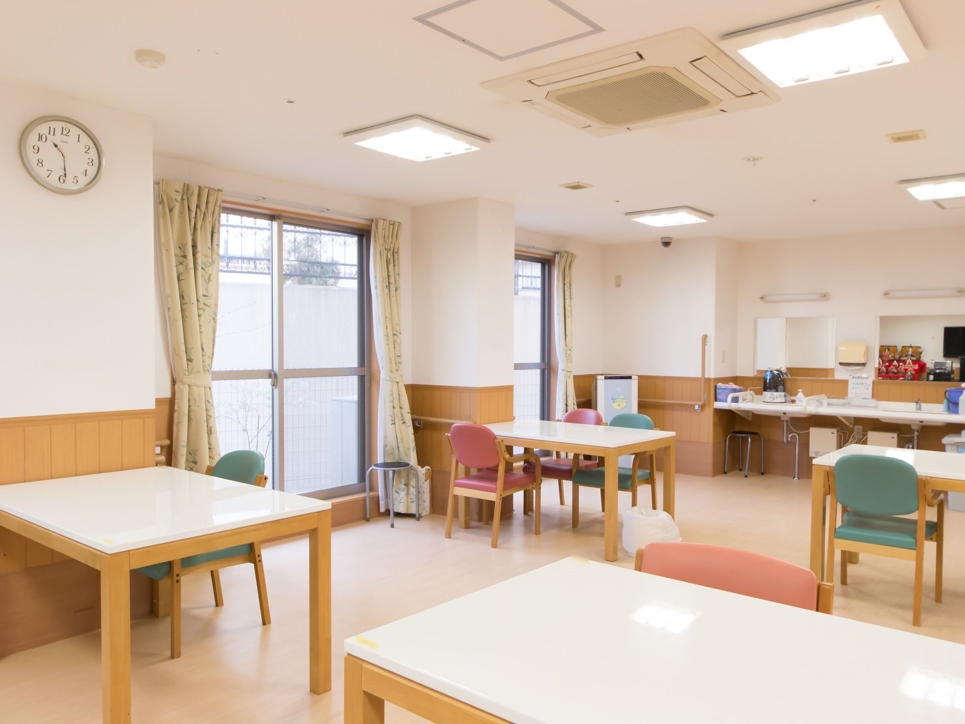 受付カウンターの側で前で手を組み微笑んで立っている女性事務員