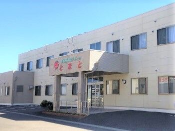 2階建ての建物は横に長くグレー系で落ち着いた雰囲気。駐車場があり、玄関には車寄せが付き、段差は解消されている。