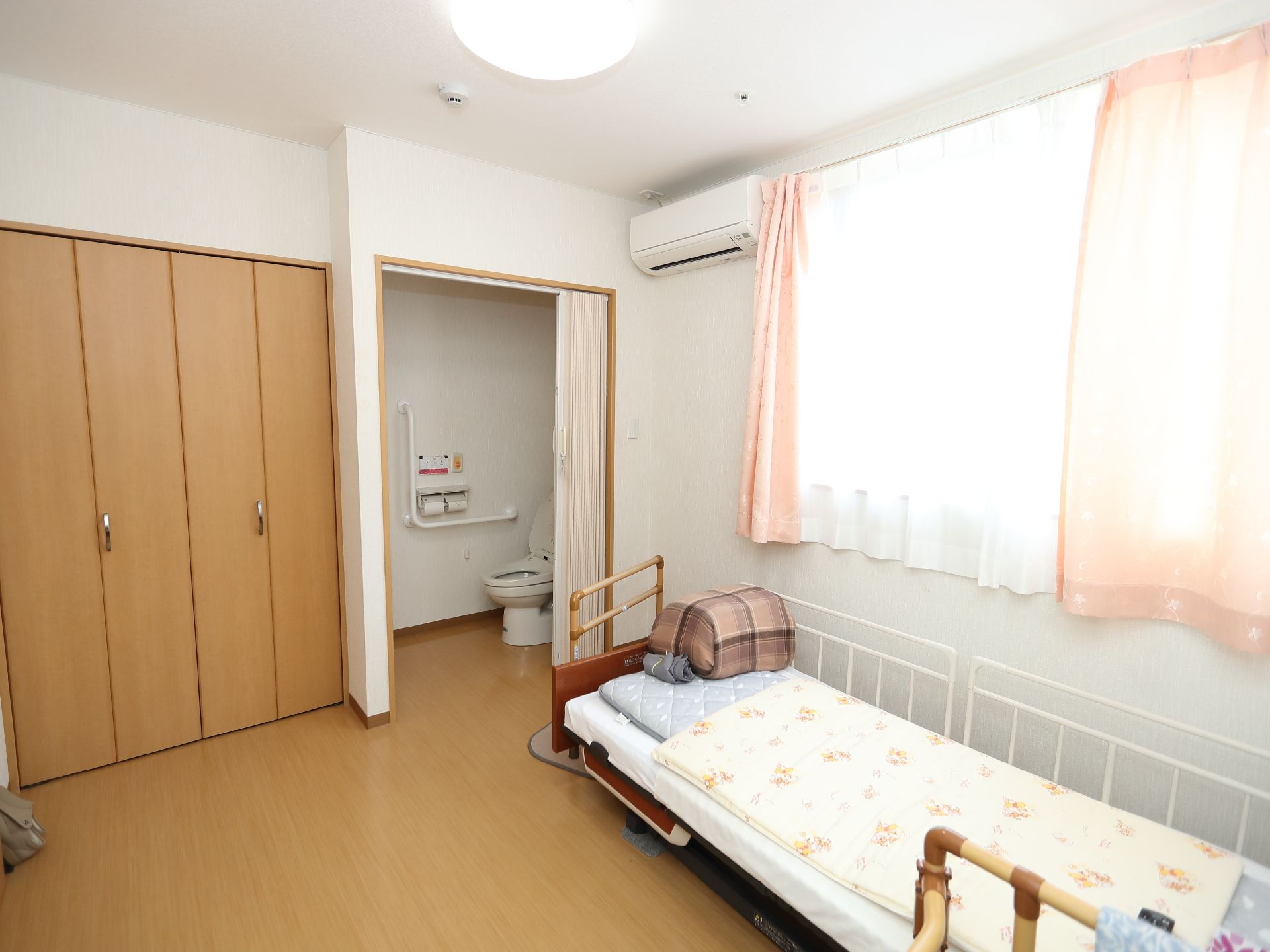 鏡を見ながら笑顔で話している高齢者とそこに寄り添介護スタッフの様子。明るい室内の写真