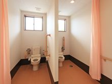 トイレが二つ並んでいる施設内のトイレの様子。カーテンで仕切られた車いす対応のトイレ