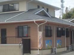 グレーの屋根、茶色の壁の建物。三角の屋根をした二階建て。