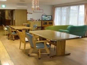 緑色のソファがあるホール。テーブルやイス、テレビなどが置かれた広々とした空間。