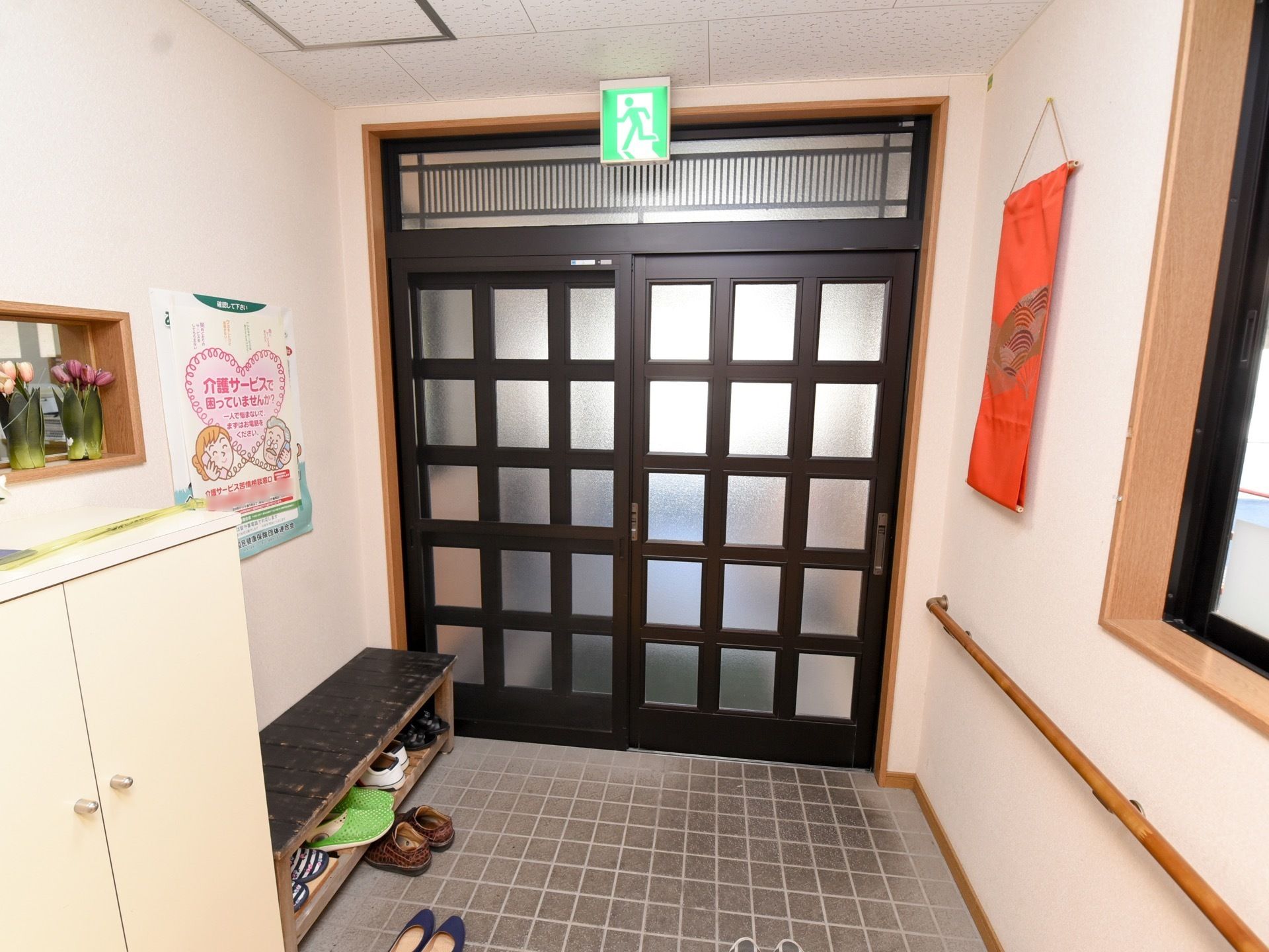 入口に入ると床は正方形の石タイルで敷かれたスペースになっている。壁にオレンジのタペストリーが下がっている。