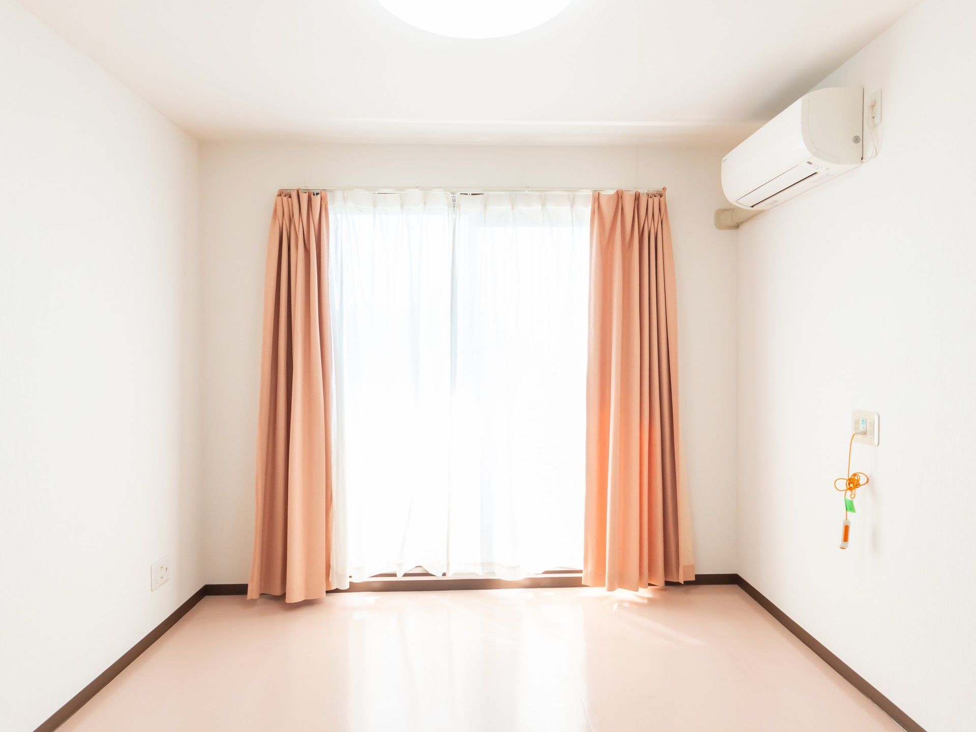 ピンク色のレースカーテンが完備されている部屋