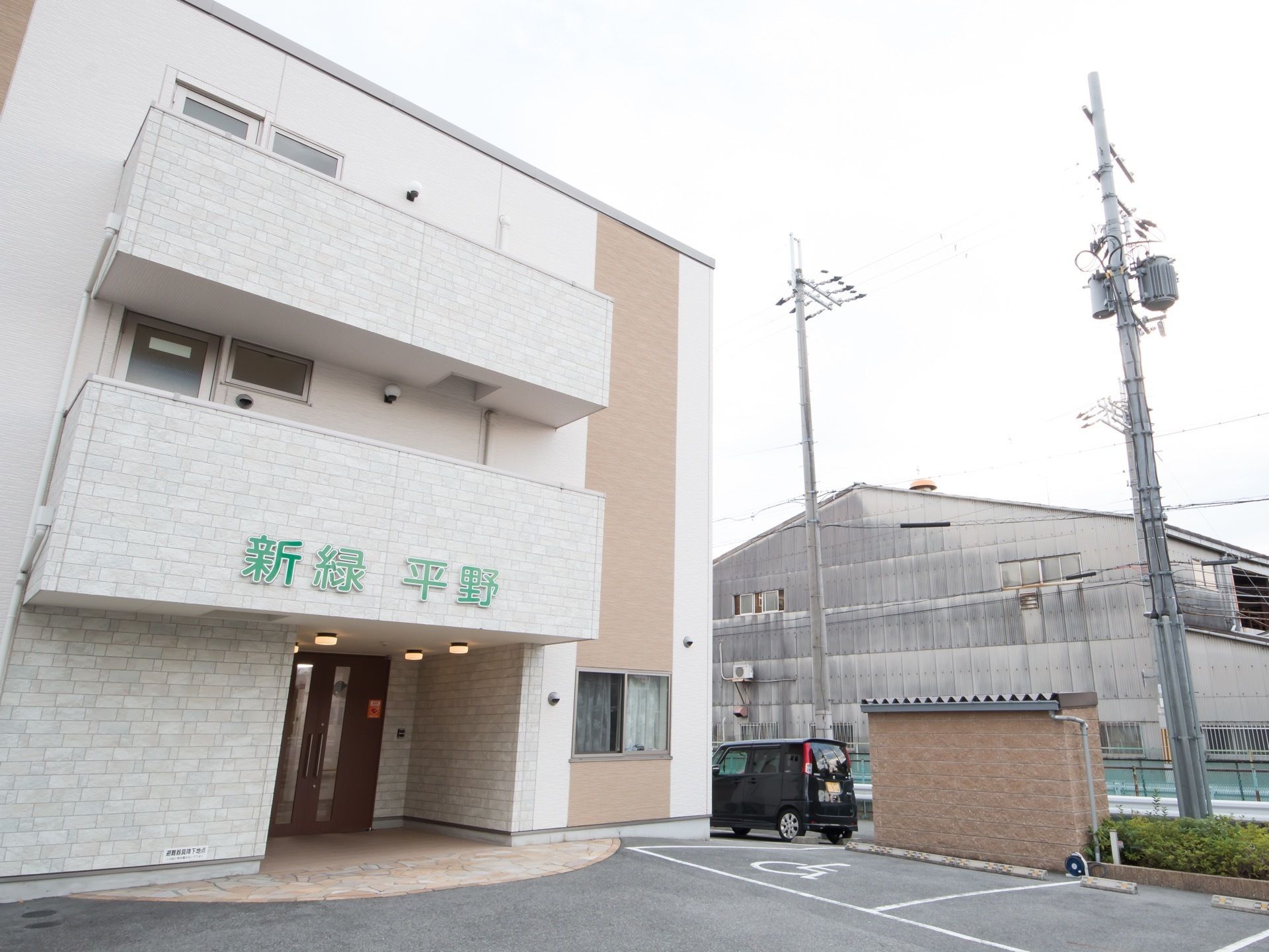 外壁には黄緑色で大きな施設の表示が設置されている。視認性がよく道路からでも容易に確認することができる。