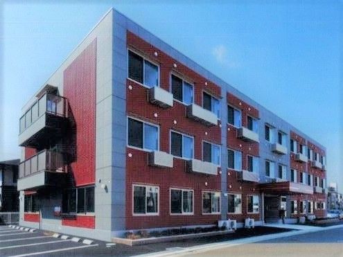 敷地内には駐車スペース。3階建てのどっしりとした建物は赤っぽい色でよく目立つ。