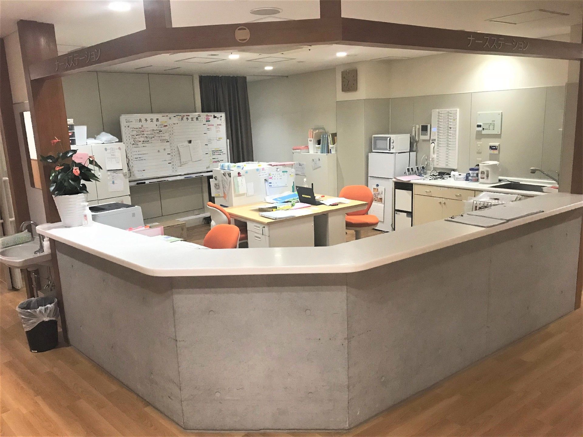 コンクリートに木製の板が乗った受付。中には机と椅子の他に冷蔵庫と電子レンジが置かれている